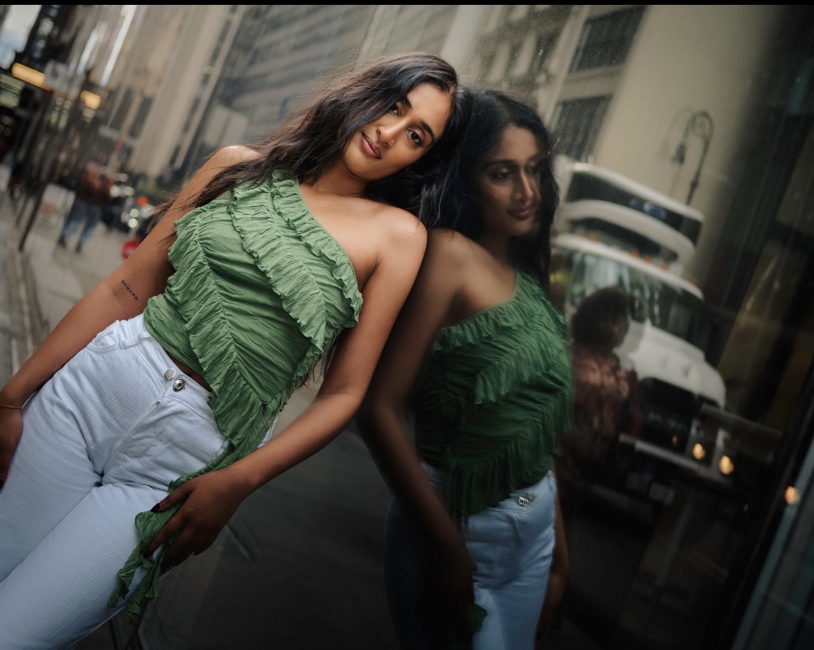 Raagini Gupta modeling beside a reflective city window in New York City
