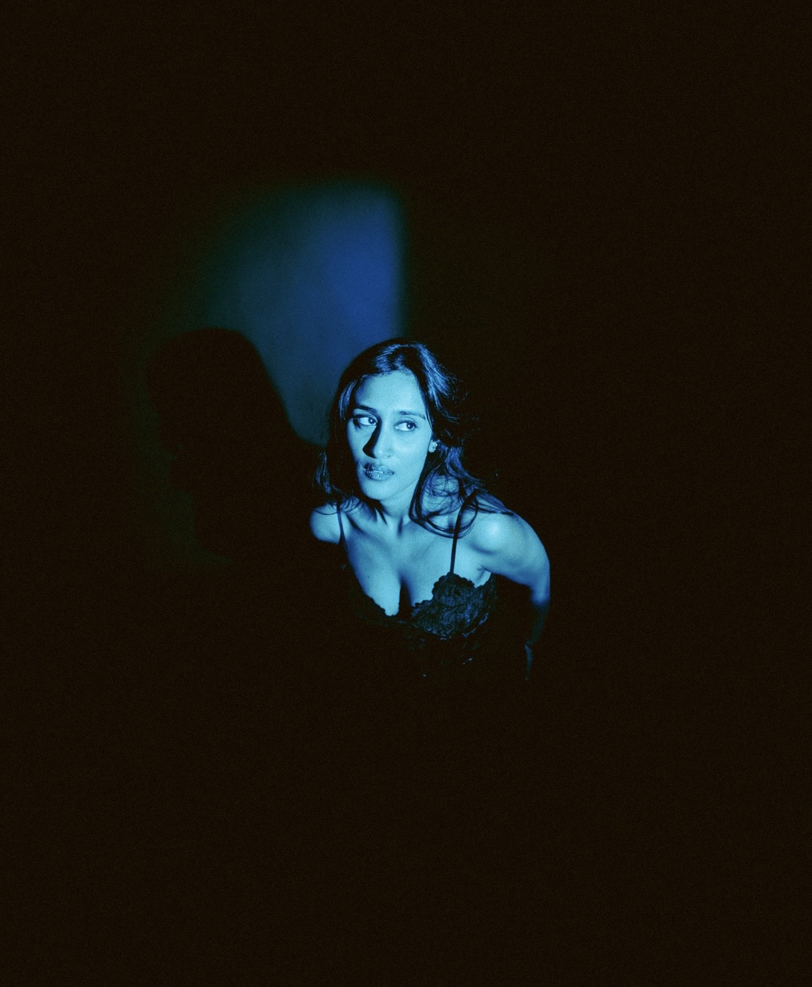Raagini Gupta looking upward in dramatic editorial lighting